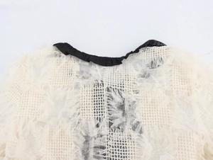 Détail d'un haut en dentelle blanche avec col rond noir et texture florale délicate