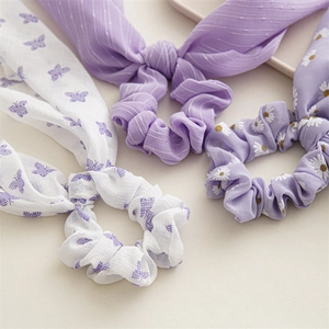 Detailed close-up of chiffon scrunchies with butterfly, stripe, and daisy prints in purple