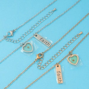 Detail of silver and rose gold heart necklaces with engraved faith metal plates