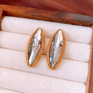 Detailed view of marquise-cut crystal earrings with gold micro-bead trim in a jewelry box