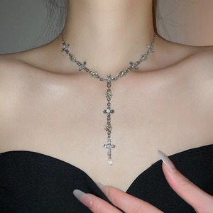 Macro detail of silver Y-shaped cross necklace with crystals and teardrop pendant