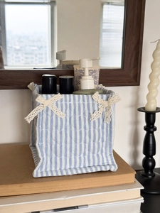 Detailed view of blue and white striped quilted storage basket with lace bows