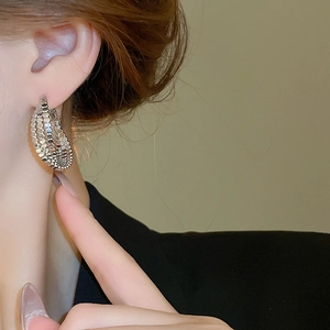 Side view of model wearing silver C-shaped beaded layered hoop earrings with metallic shine