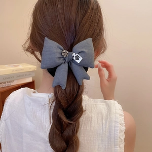 Dettaglio del fiocco in tessuto grigio scuro con strass e ciondolo camelia sui capelli