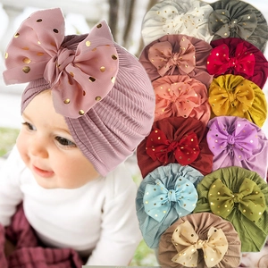 Detail von Baby-Turbanen mit Rippstrick und goldenen Punktschleifen in bunten Farben