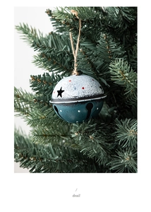 Detail of vintage blue and white metal Christmas bell with star cutouts on tree branch