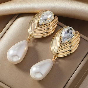 Elegant gold earrings featuring crystal drop and pearl tassels on champagne satin