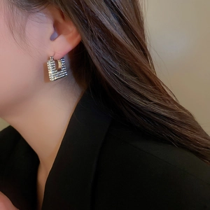 Dettaglio di un orecchino geometrico quadrato argento con strass su una modella