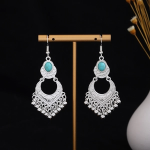 Close-up of vintage tribal silver earrings with turquoise stones and hollow tassel details