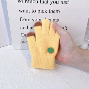 Yellow knit children gloves with brown touchscreen fingertips and green smiley face button