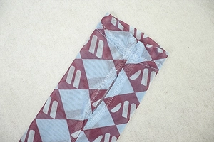 Detail of sheer mesh fabric with burgundy and blue geometric prints and seam stitching