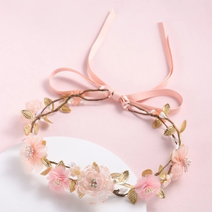 Detail of pink silk flowers and golden metal leaves on an adjustable floral headband