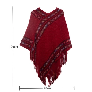 Detail view of red knitted poncho with geometric patterns, fringe tassels and 100x98cm size