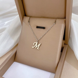 Detailed view of silver letter M pendant on soft silk background in a premium jewelry box