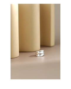 Detailed macro view of silver minimalist ring with irregular hammered texture on metal surface