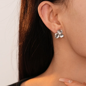 Detailed view of a silver floral earring with hammer texture and central pearl inlay