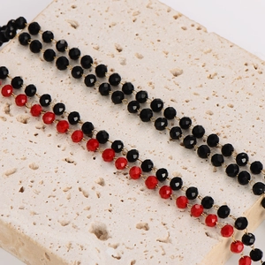 Minimalist beaded necklace with black and red faceted beads on stone background