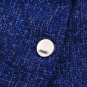 Close-up of blue tweed fabric texture with a polished silver button on a sleeveless suit