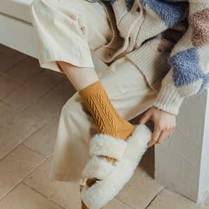 Détail de chaussettes en tricot torsadé jaune gingembre avec pantoufles en peluche blanche