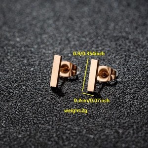 Boucles d'oreilles barres rectangulaires minimalistes en or rose sur fond texturé noir