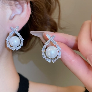 Detailed view of silver zircon pearl earrings with baguette-cut crystals on ear