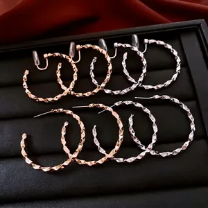Geometric faceted silver hoop earrings in rose gold and silver displayed on black leather