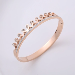 Macro detail of rose gold crown bangle featuring pavé crystals and click clasp closure