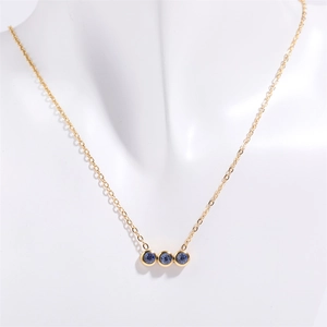 Collana dorata in acciaio inox con tre pietre di nascita blu su espositore a busto bianco