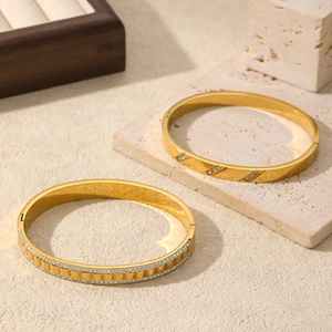 Elegant gold-plated stainless steel bangles with crystal inlay on a stone background