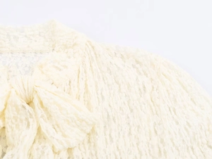 Detailed view of the delicate lace fabric and bow tie decoration on the neckline
