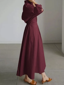 Détail d'une robe longue bordeaux à manches longues avec capuche, taille ajustée et tissu doux