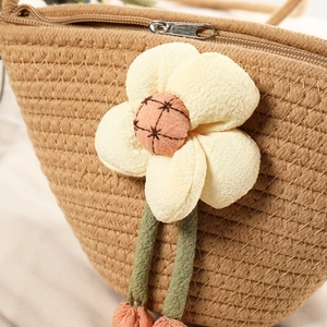 Close-up of woven cotton rope shell bag with 3D floral decoration and pink tassel detail