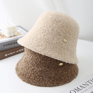 Faux shearling lamb wool bucket hats in beige and brown with elegant golden logo detail
