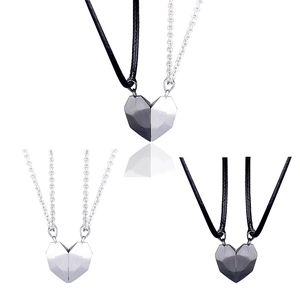 Detail of magnetic heart pendant couple necklaces in black and silver tone