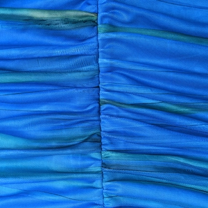 Close-up of blue mesh fabric texture with vertical seams and ruffled pleats on the dress