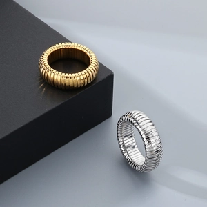 Detailed view of textured wavy gold and silver snake rings on a geometric modern backdrop