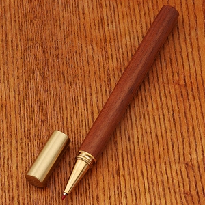 Detailed macro shot of vintage bamboo-style brass pen on a textured wooden background