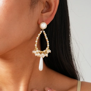 Close-up of model wearing gold baroque pearl drop earrings with hollow waterdrop design