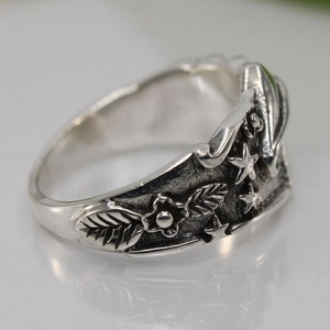 Vintage silver ring with embossed flower, star and leaf patterns in a retro style