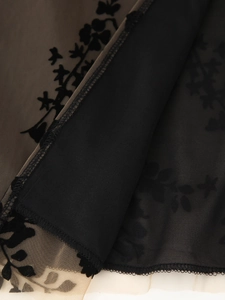Détail d'une robe en mesh noir avec flocage floral élégant et bordures finement cousues