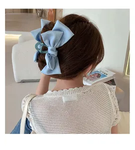 Detail of a large light blue satin bow hair claw clip worn on a woman's hair
