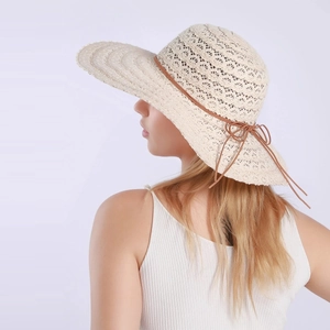 Detail view of woven straw hat texture with an elegant brown bow and wide brim design