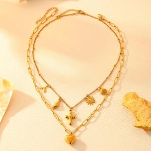 Macro shot of gold double-layer necklace with cross, heart, shell and fish tail pendants