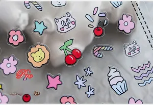 Macro shot of ultra-thin nail art stickers featuring pink cats, cherries and floral motifs