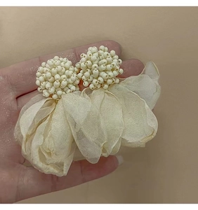 Detail of cream floral tassel earring featuring woven beads and translucent gauze petals