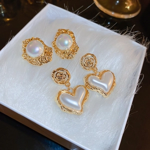 Close-up of vintage flower and pearl heart earrings in a jewelry box display
