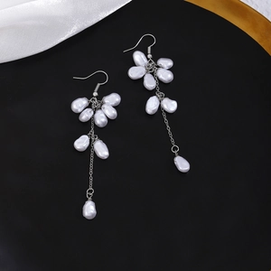 Detail of elegant butterfly pearl drop earrings with silver fringe and long tassel design