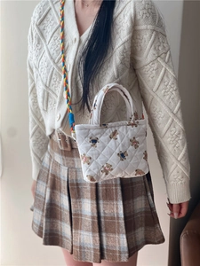 Quilted mini crossbody bag with cute bear print and colorful braided strap shown on model