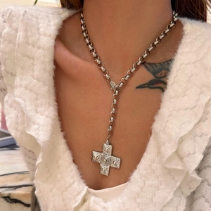 Macro detail of a vintage engraved cross pendant on a thick round link chain necklace