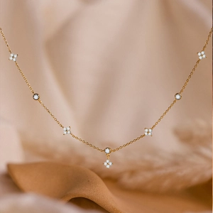 Detail der goldenen Kleeblatt-Halskette mit funkelnden Zirkonia-Blumen auf feiner Kette